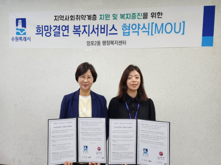 신용남 망포2동장과 김승경 수원시자원봉사센터 영통분소 팀장이 협약을 체결하고 사진촬영을 하고 있다.