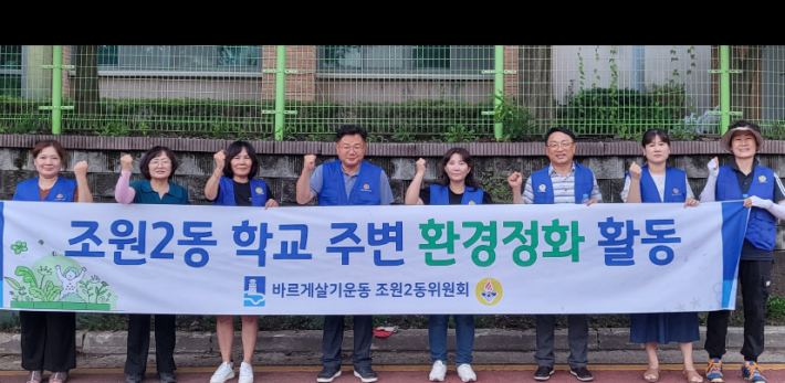 바르게살기위원회위원들이 산책길 가꾸기 전 홍보 현수막을 들고 있다.