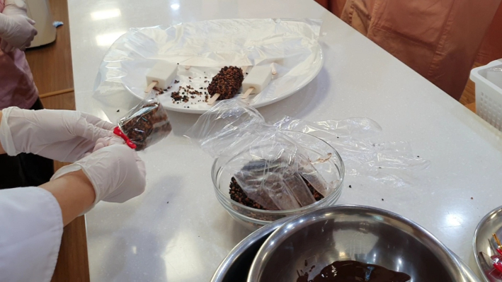 만들어진 떡에 초콜릿을 묻히고 크런치를 묻히고 있다.