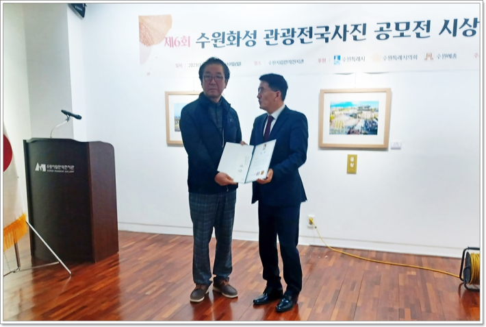 수원특례시의회 김기정 의장이 금상 수상자이 박수덕 사진작가에게 상장을 수여하고 기념사진을 촬영하고 있다.