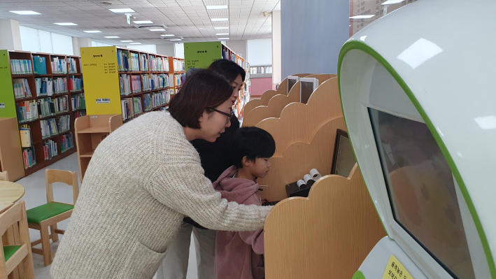 지혜샘도서관 김진희 차장이 도서관을 찾은 어린이에게 인터넷으로 책을 검색하는 과정을 알려주는 모습