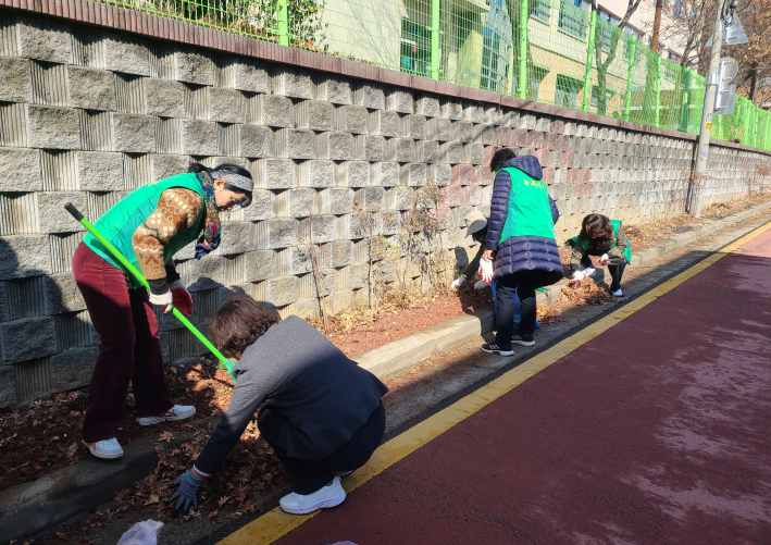 단체원들이 손바닥정원의 낙엽을 치우고 있다.