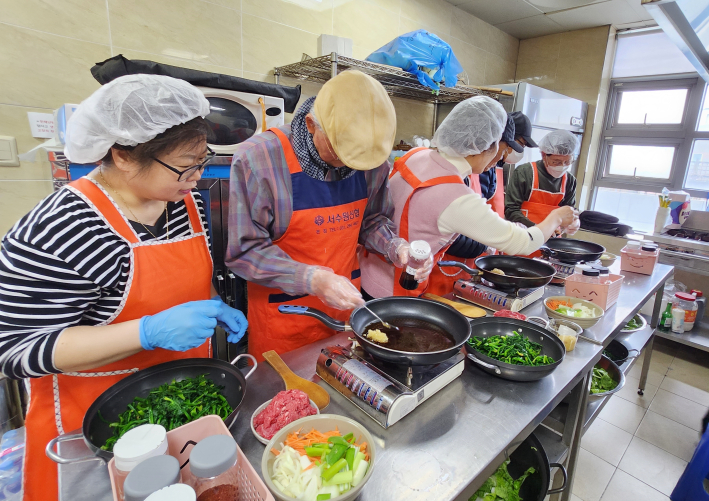 지역사회보장협의체 위원들과 어르신들이 함께 요리를 하고 있다.