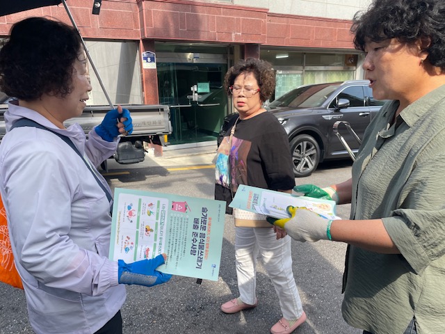 우만1동 통장협의회 회원들이 올바른 쓰레기 분리배출 을 방법이 적힌 홍보전단지를 시민에게 전달하고 있다.