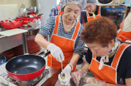  어르신이 지역사회보장협의체 위원과 함께 음식을 만들고 있다.