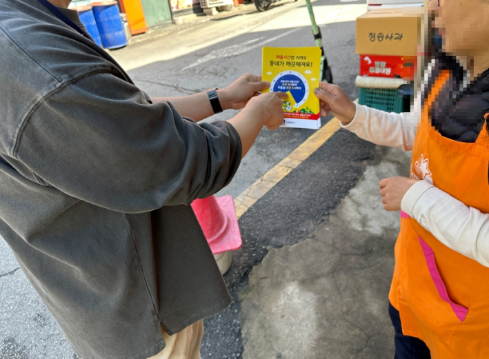 지역 주민에게 배출시간 준수 홍보물을 배부하며 설명중이다.