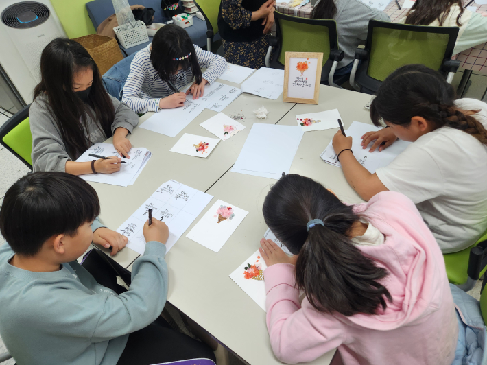 캘리그라피 글자를 연습하는 학생들
