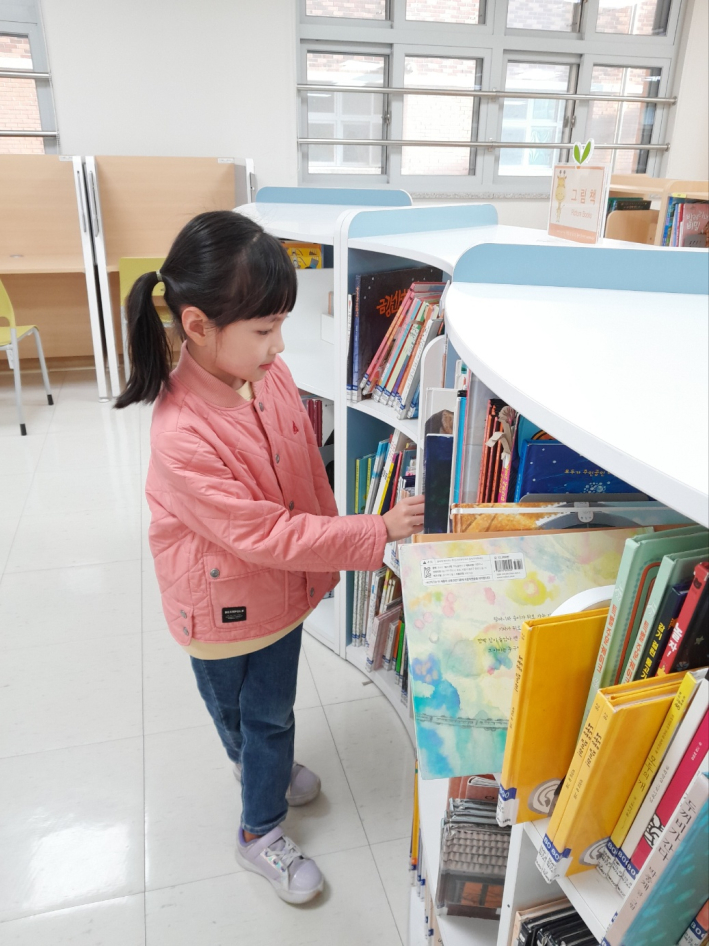 한 어린이가 서가에서 책을 고르고 있다.