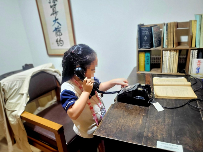 한 유치원생이 다이얼 전화기 체험을 해 보고 있다.