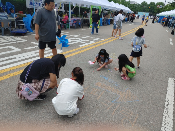 2024년 제1회 구운동 자동차 없는 날에 참여한 아이들이 도로에 그림을 그리고 있다.