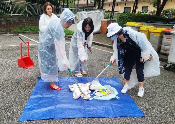 조원2동 통장협의회가 쓰레기 봉투를 파봉하여 분리배출 상태를 점검하고 있다.