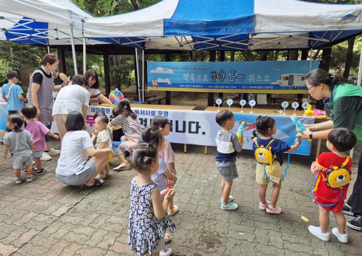 아이들이 신명 새마을문고 앞마당에서 '책속으로 풍덩 흠뻑 퀴즈쇼'에 참여 하고 있다.