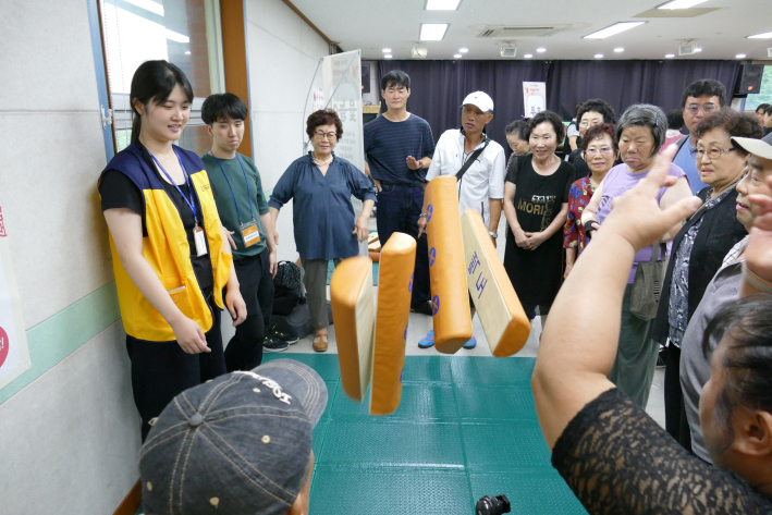 우만종합사회복지관이 지난 12일 한가위 한마당 민속놀이 잔치를 열었다. 윷놀이 부스에 참여한 주민이 윷을 던지고 있다.