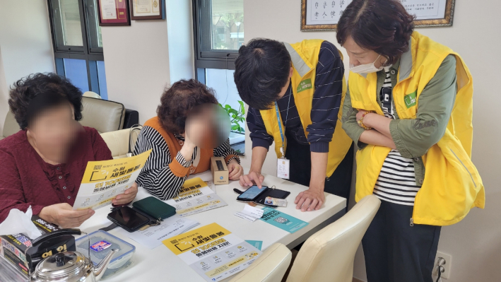 권선2동 행정복지센터 직원들이 경로당서 복지위기알림 앱의 설치를 도와드리는 모습