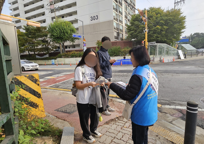 등교하는 학생에게 학교폭력 예방 리플릿을 나누어주고 있다.