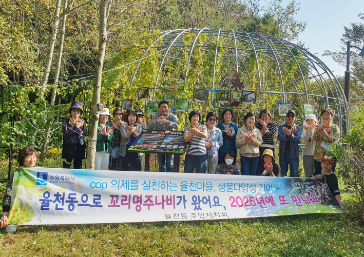 율천동 주민자치회가 꼬리명주나비 정원 갤러리 조성후 기념사진을 촬영하고 있다.