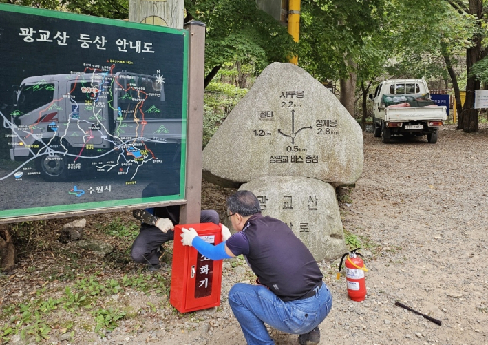 광교산 주요 등산로에 소화기를 설치하고 있다