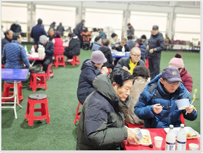 돔 경기장 안에 접이식 식탁 위에서 행사에 참석한 시민과 선수들이 함께 점심식사를 하고 있다.