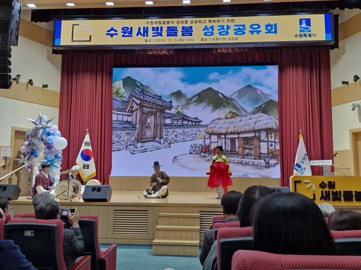 성과 축하 공연 장면. 수원새빛돌봄을 주제로 한 퓨전 마당극을 펼쳤다. 극 중 인물이 수원새빛돌봄 사업을 판소리 사설 형식으로 소개하고 있다.   