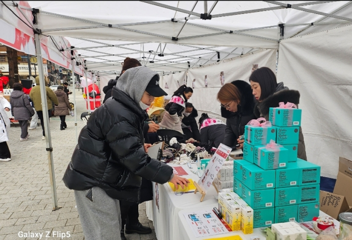 바자회 방문객이 진열된 상품을 살펴보고 있다    