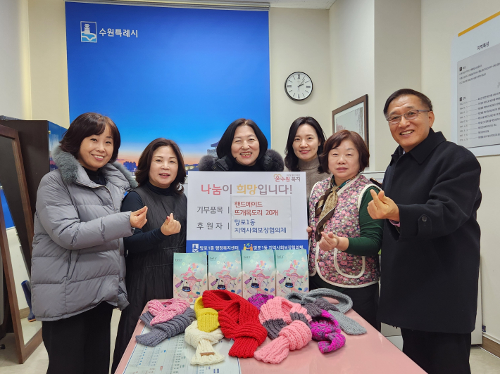 망포1동 지역사회보장협의체 위원들이 직접 짠 목도리를 망포1동 행정복지센터에 전달하고 있다.