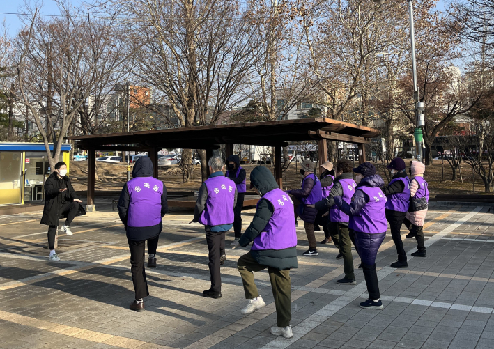 송죽동 아름다운 동행 동네 한 바퀴 참여자들이 걷기 운동 전 스트레칭을 하고 있다.