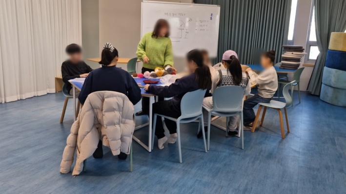 선생님이 숄더 크로즈백을 만드는 아이들을 보며 주의를 주고 있다.