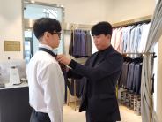 슈트패브릭 수원점 류동현 지점장이 넥타이 매는 법을 세심하게 지도하는 모습