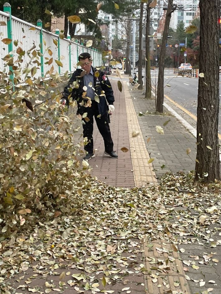 관리사무소 직원이 송풍기를 이용하여 낙엽을 불어 내고 있다.