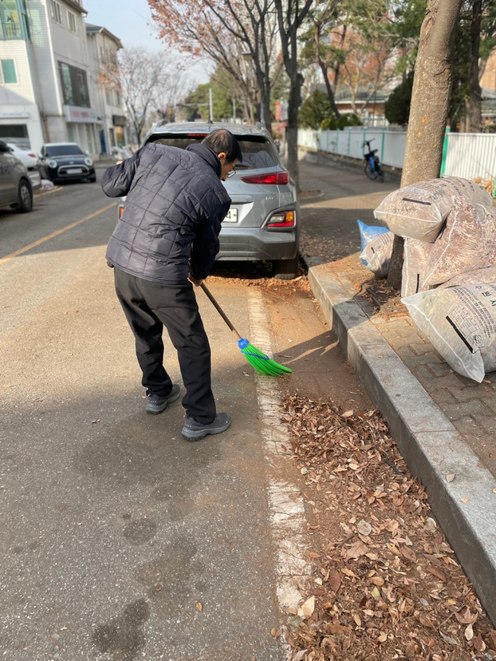 지역 주민이 낙엽을 쓸어 모으고 있다.