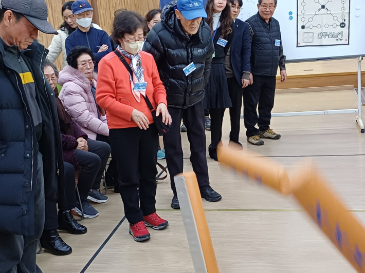 긴장한 모습으로 떨어지는 윷을 바라보는 윷놀이 전경