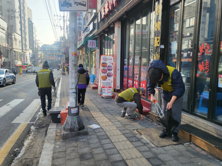 거리노숙인특화자활참여 노숙인들이 거리를 걸어다니면서 쓰레기를 줍고 있다.