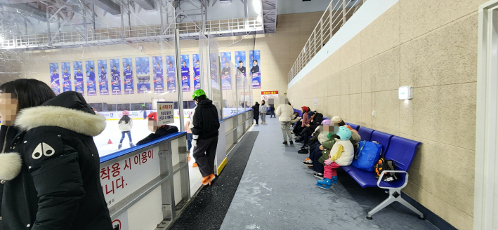 빙상장 밖에서 쉬고있는 사람들