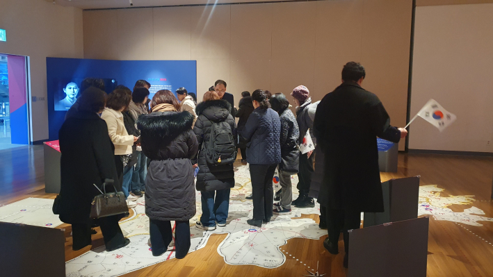 관람객이 태극기를 들고 역사 현장으로 찾아가는 듯하다