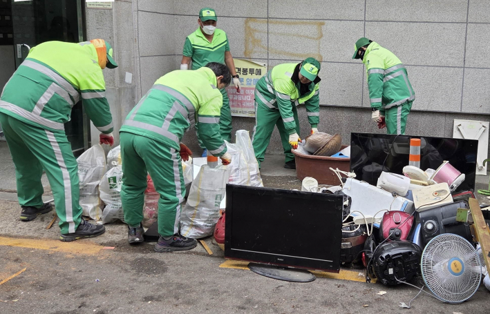 조원1동 행정복지센터 소속 환경관리원들이 저장강박증이 있는 가정에서 나온 쓰레기들을 정리 하고 있다.