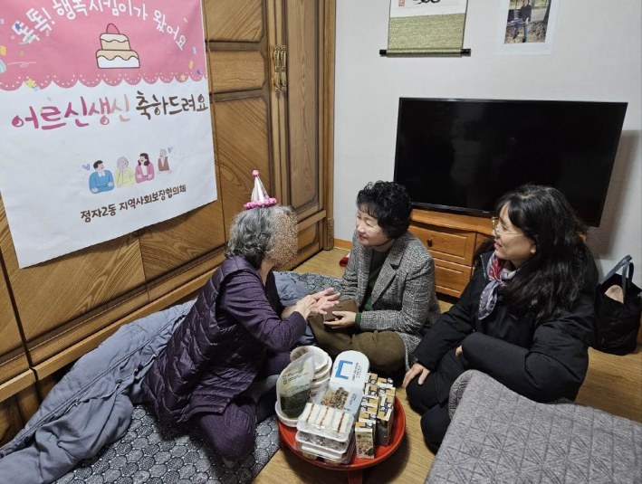 어르신에게 생신상을 차려드리고 따뜻한 담소를 나누고 있다