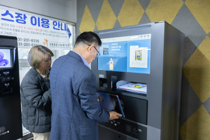 영통종합사회복지관 이필신 관장이 새로 구축된 RFID시스템을 점검하고 직접 이용하는 모습이다.
