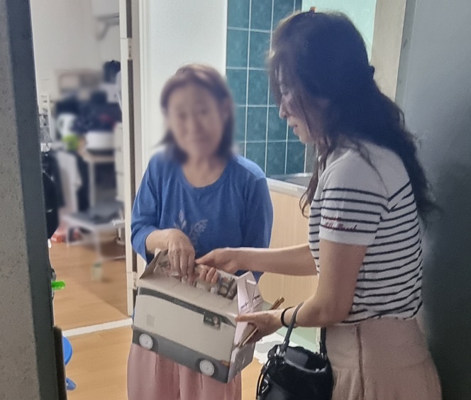 매탄4동 지역사회보장협의체 위원들이 고독사 위험가구에 건강음료 꾸러미를 전달하고있다.