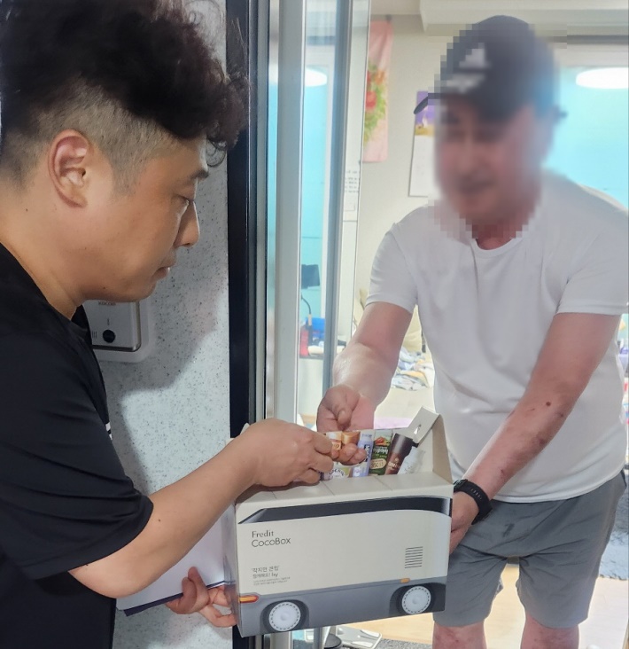 매탄4동 지역사회보장협의체 위원들이 고독사 위험가구에 건강음료 꾸러미를 전달하고있다.