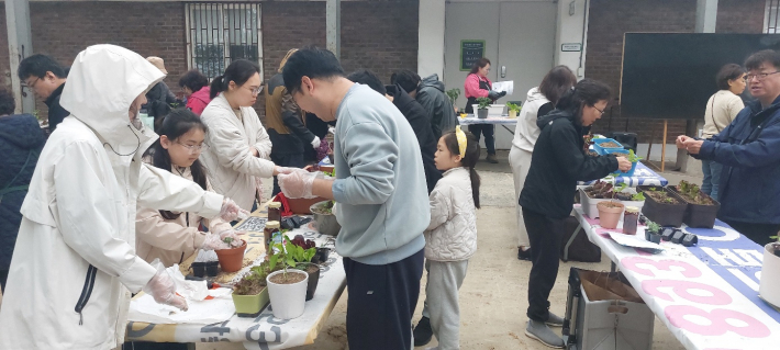 교육 참가 가족이 상자텃밭에 농작물을 심고 있다.