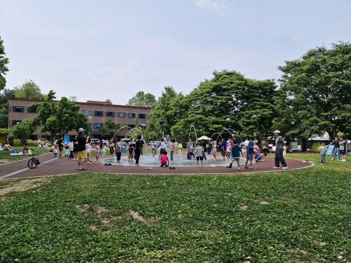 '생생1990' 앞에 바닥 분수대. 어린아이들이 물놀이를 즐기고 있다.