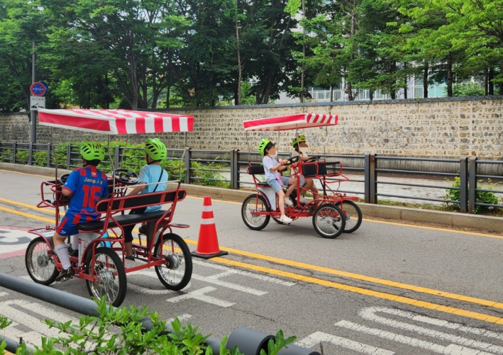 아이들이 차없는 도로에서 이색자전거(마차형)를 타고 있다.
