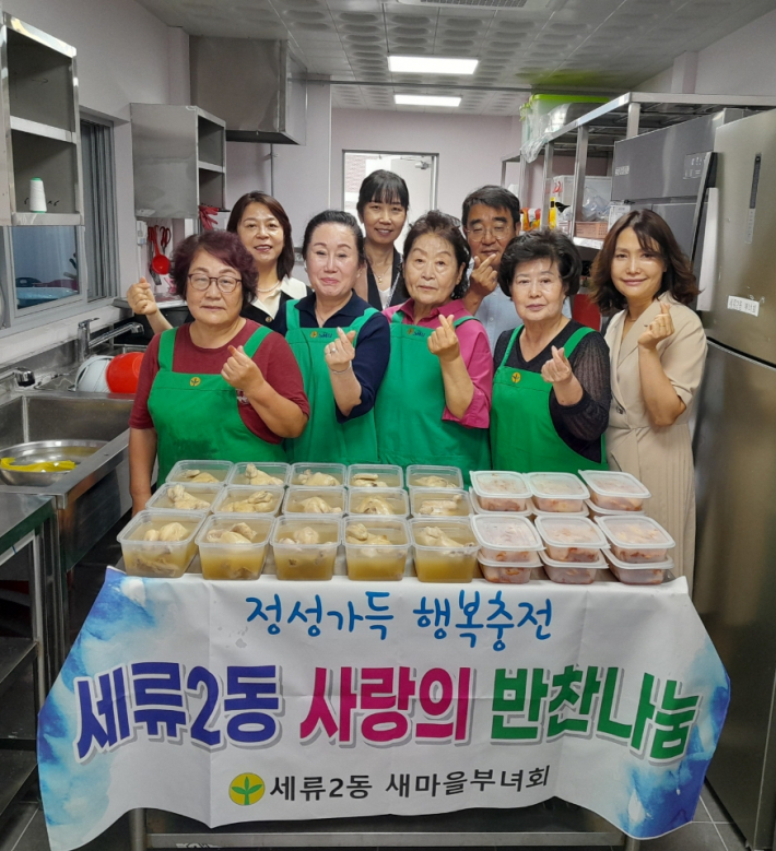 세류2동 새마을부녀회장 및 회원, 세류2동장 등이 맛있게 조리된 삼계탕 앞에 모여 있다.