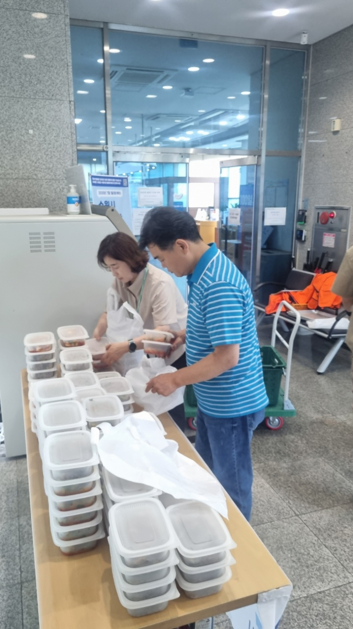 지역사회보장협의체 위원들이 정성스럽게 반찬을 전달하기 위해 포장하고 있다.