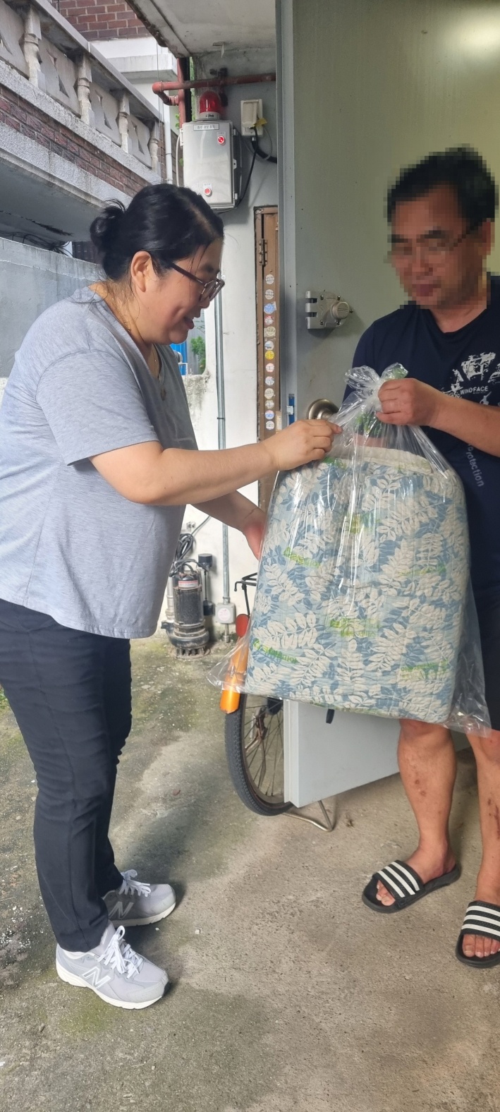 지역사회보장협의체 위원이 세탁된 빨래를 서비스 대상자에게 전달하고 있다.