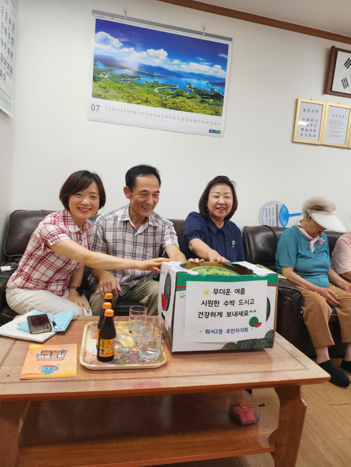 양순옥 화서2동주민자치회장과 지은아 화서2동장이 백승철 화서2동경로당협의회장에게 수박을 전달하고 있다.