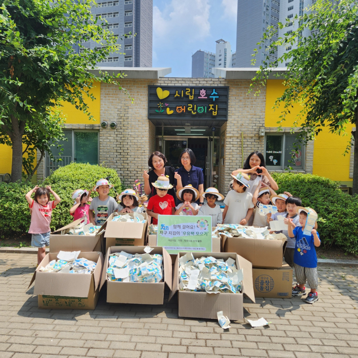 시립호수어린이집 원아들이 6개월간 모은 우유팩과 함께 기념촬영을 하고 있다.