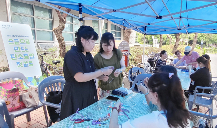 정자3동에서 진행한 탄소중립 캠페인 체험부스에서 재생종이를 활용한 키링을 만들고 있다.