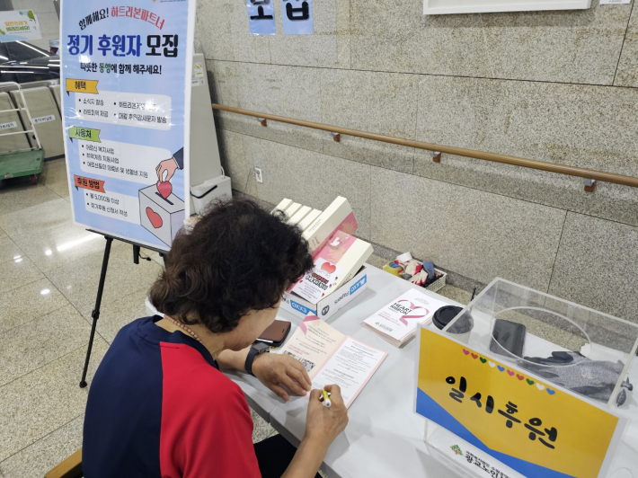 후원 캠페인 앞에서 후원을 약정하는 어느 어르신