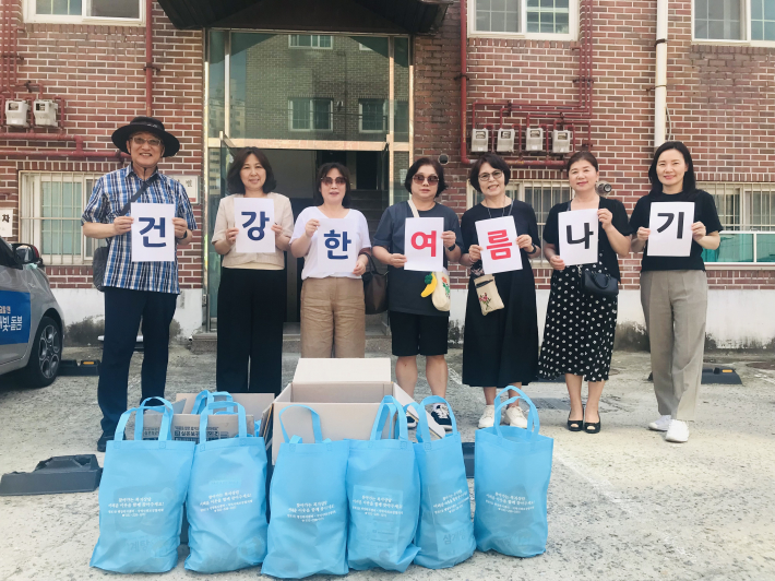 지사협 위원들과 망포1동장(왼쪽 두번째)이 홀몸 어르신들께 드릴 보양식 꾸러미를 놓고 기념촬영을 하고 있다.